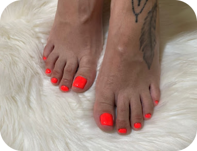 Pés com unhas pintadas em vermelho neon sobre tapete de pelo branco